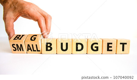 Big or small budget symbol. Businessman turns wooden cubes and changes words Small budget to Big budget. Beautiful white table white background, copy space. Business big or small budget concept. Big or small budget symbol. Businessman turns wooden cubes and changes words Small budget to Big budget. Beautiful white table white background, copy space. Business big or small budget concept. 107040092