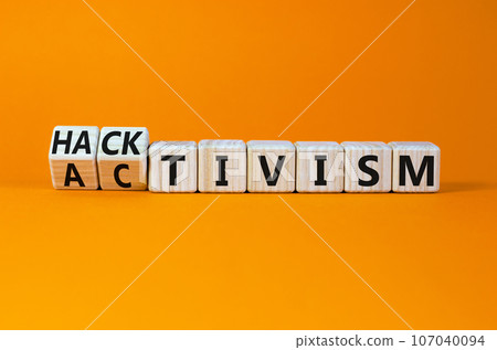 Activism or hacktivism symbol. Turned wooden cubes and changed the concept word Activism to Hacktivism. Beautiful orange table orange background, copy space. Business activism or hacktivism concept. Activism or hacktivism symbol. Turned wooden cubes and changed the concept word Activism to Hacktivism. Beautiful orange table orange background, copy space. Business activism or hacktivism concept. 107040094