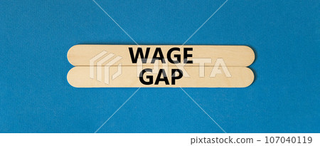 Wage gap symbol. Concept words Wage gap on beautiful wooden stick on a beautiful blue table blue background. Business, support and wage gap concept. Copy space. Wage gap symbol. Concept words Wage gap on beautiful wooden stick on a beautiful blue table blue background. Business, support and wage gap concept. Copy space. 107040119