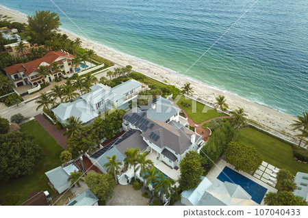 Big new residential house in USA with rooftop covered with solar photovoltaic panels for producing of clean ecologic electrical energy in suburban rural area. Concept of autonomous home on sea shore 107040433