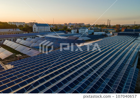 Aerial view of solar power plant with blue photovoltaic panels mounted on industrial building roof for producing green ecological electricity. Production of sustainable energy concept 107040657
