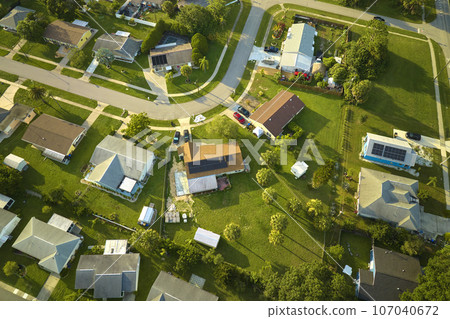 Aerial view of small town America suburban landscape with private homes between green palm trees in Florida quiet residential area Aerial view of small town America suburban landscape with private homes between green palm trees in Florida quiet residential area 107040672