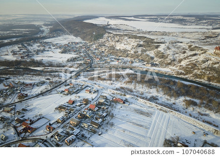 Aerial view of residential houses with snow covered roofops in suburban rural town area in winter Aerial view of residential houses with snow covered roofops in suburban rural town area in winter 107040688