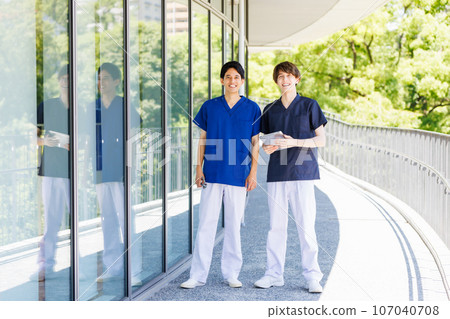Medical workers wearing scrubs walking down the hallway Medical workers wearing scrubs walking down the hallway 107040708