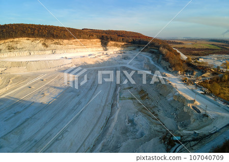 Aerial view of open pit mining site of limestone materials for construction industry with excavators and dump trucks Aerial view of open pit mining site of limestone materials for construction industry with excavators and dump trucks 107040709