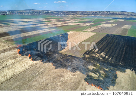 Aerial view of grassland field burning with red fire during dry season. Natural disaster and climate change concept Aerial view of grassland field burning with red fire during dry season. Natural disaster and climate change concept 107040951