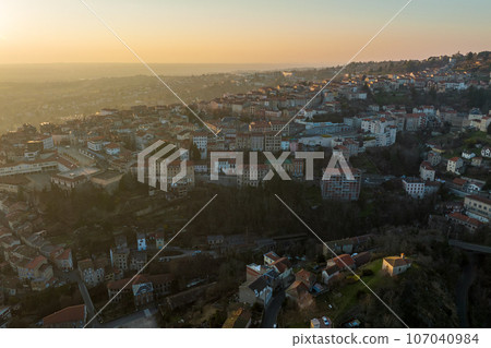 Aerial view of dense historic center of Thiers town in Puy-de-Dome department, Auvergne-Rhone-Alpes region in France. Rooftops of old buildings and narrow streets at sunset 107040984
