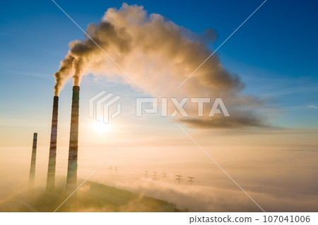 Aerial view of coal power plant high pipes with black smoke moving up polluting atmosphere at sunrise. Aerial view of coal power plant high pipes with black smoke moving up polluting atmosphere at sunrise. 107041006