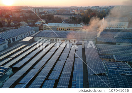 Aerial view of blue photovoltaic solar panels mounted on industrial building roof for producing green ecological electricity. Production of sustainable energy concept Aerial view of blue photovoltaic solar panels mounted on industrial building roof for producing green ecological electricity. Production of sustainable energy concept 107041036