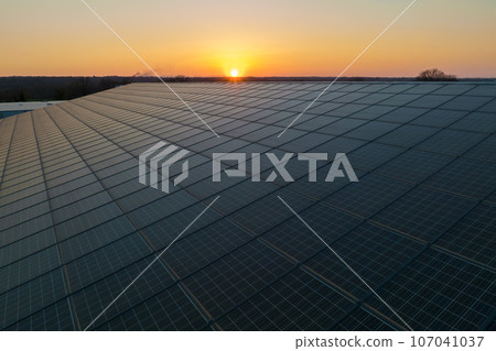Aerial view of blue photovoltaic solar panels mounted on industrial building roof for producing green ecological electricity. Production of sustainable energy concept Aerial view of blue photovoltaic solar panels mounted on industrial building roof for producing green ecological electricity. Production of sustainable energy concept 107041037