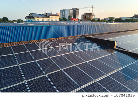 Aerial view of blue photovoltaic solar panels mounted on industrial building roof for producing green ecological electricity. Production of sustainable energy concept Aerial view of blue photovoltaic solar panels mounted on industrial building roof for producing green ecological electricity. Production of sustainable energy concept 107041039