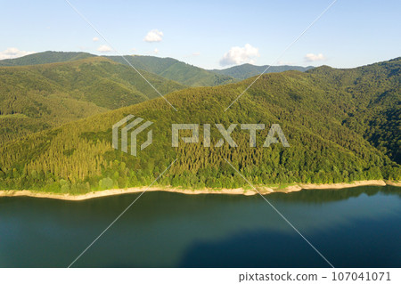 Aerial view of big lake with clear blue water between high mountain hills covered with dense evergreen forest. Aerial view of big lake with clear blue water between high mountain hills covered with dense evergreen forest. 107041071