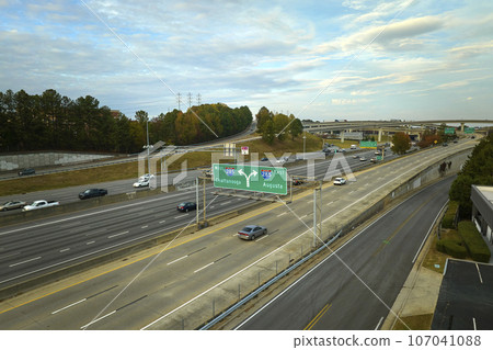 Aerial view of american freeway intersection with fast moving cars and trucks. USA transportation infrastructure concept Aerial view of american freeway intersection with fast moving cars and trucks. USA transportation infrastructure concept 107041088