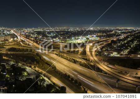 Aerial view of american freeway intersection at night with fast driving cars and trucks in Miami, Florida. View from above of USA transportation infrastructure Aerial view of american freeway intersection at night with fast driving cars and trucks in Miami, Florida. View from above of USA transportation infrastructure 107041091