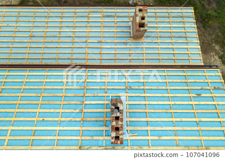 Aerial view of a wooden roof frame of brick house under construction. 107041096
