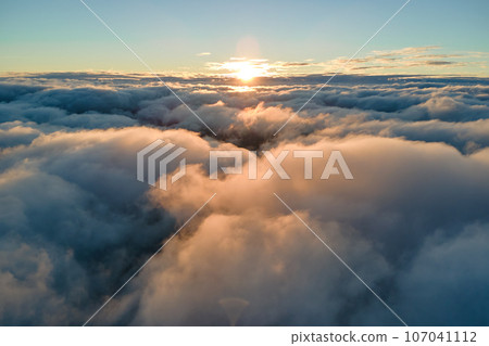 Aerial view from airplane window at high altitude of dense puffy cumulus clouds flying in evening 107041112