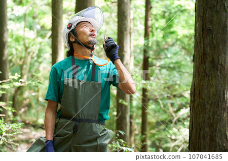 一名戴頭盔的男子在森林中用對講機說話的圖像、森林官員、自然保護官員 107041685