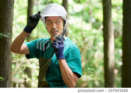 Image of a man wearing a helmet talking on a walkie-talkie in the forest, forest officer, nature conservation officer 107041688