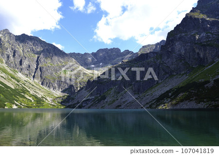 A green water lake in mountains cloudy weather. 'Czarny staw gasienicowy' lake in Tatry, Poland A green water lake in mountains cloudy weather. 'Czarny staw gasienicowy' lake in Tatry, Poland 107041819