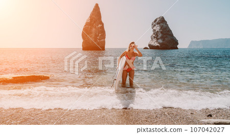 Woman sea sup. Close up portrait of happy young caucasian woman with blond hair looking at camera and smiling. Cute woman portrait in red bikini posing on sup board in the sea Woman sea sup. Close up portrait of happy young caucasian woman with blond hair looking at camera and smiling. Cute woman portrait in red bikini posing on sup board in the sea 107042027