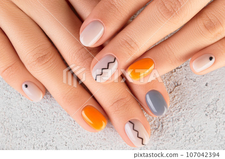 Manicured womans hands close up on gray background. Minimal spring autumn nail design Manicured womans hands close up on gray background. Minimal spring autumn nail design 107042394