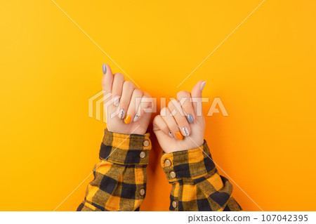 Beautiful womans hands with minimal nail design on orange background. Manicure, pedicure beauty salon concept 107042395