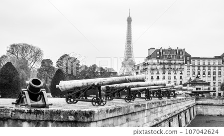 Historical cannons at Les Invalides and parisian cityscape with Eiffel Tower, Paris, France. Black and white photography. Black and white photography. Historical cannons at Les Invalides and parisian cityscape with Eiffel Tower, Paris, France. Black and white photography. Black and white photography. 107042624