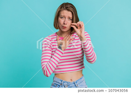 Woman showing a little bit gesture with sceptic smile showing minimum sign measuring small size Woman showing a little bit gesture with sceptic smile showing minimum sign measuring small size 107043056