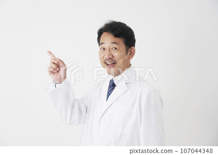 Middle-aged doctor pointing to the left, white background 107044348
