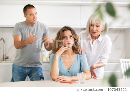 Adult man quarreling with adult and elderly woman in kitchen 107045321