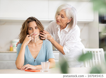 Elderly woman quarreling with adult woman in kitchen 107045415
