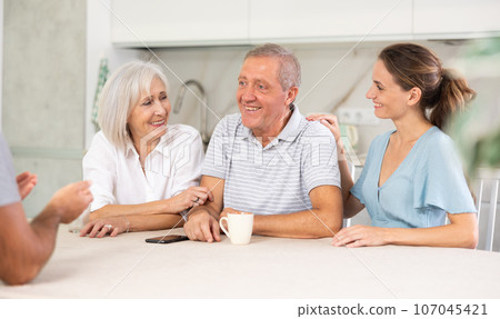 Married couple and senior parents talk about home life 107045421