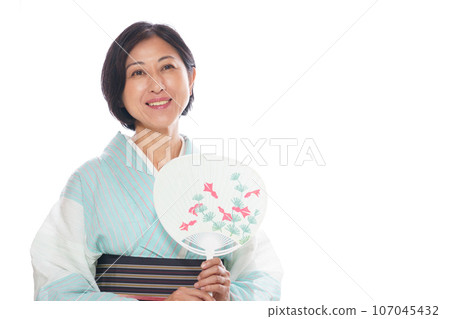 A smiling middle-aged woman in a kimono cooling off with a fan A smiling middle-aged woman in a kimono cooling off with a fan 107045432
