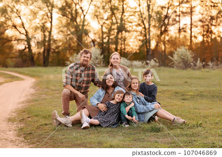 Large family smiles together in sunny field Large family smiles together in sunny field 107046869