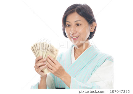 Middle-aged woman wearing summer kimono and holding bills 107047255