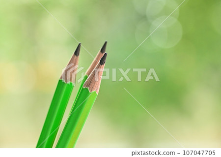 three sharp green wooden pencil on blur nature background with bokeh three sharp green wooden pencil on blur nature background with bokeh 107047705
