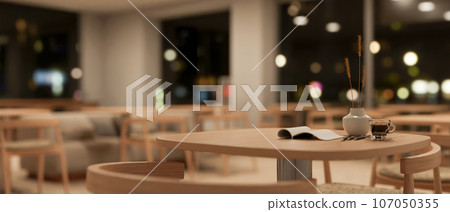 Close-up image of a wooden round table in a cozy minimalist coffee shop or co-working space at night 107050355
