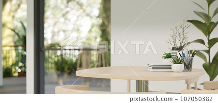A copy space on a wooden table in a modern contemporary bright room with houseplants and white wall. 107050382