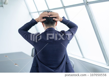 Rear view of a man holding his head Rear view of a man holding his head 107050556