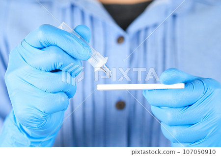 The doctor holds a COVID-19 swab collection, wears blue gloves and a PPE protective mask, and carries a test tube to collect the OP NP and test coronavirus. The doctor holds a COVID-19 swab collection, wears blue gloves and a PPE protective mask, and carries a test tube to collect the OP NP and test coronavirus. 107050910