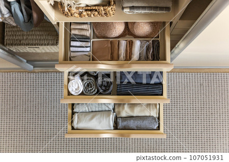 Modern wardrobe with stylish women's clothing. Drawer with underwear, t-shirts, socks and shorts. The concept of storage and order. 107051931