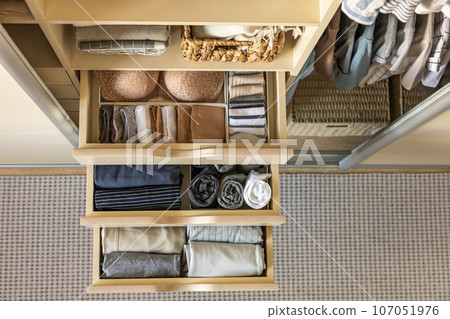 Modern wardrobe with stylish women's clothing. Drawer with underwear, t-shirts, socks and shorts. The concept of storage and order. 107051976