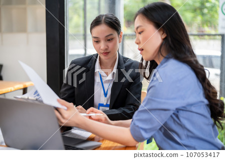 A focused Asian businesswoman is examining a business financial data report with her colleague A focused Asian businesswoman is examining a business financial data report with her colleague 107053417