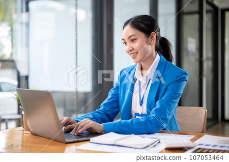 A professional and beautiful Asian businesswoman managing her work on her laptop at her desk. 107053464