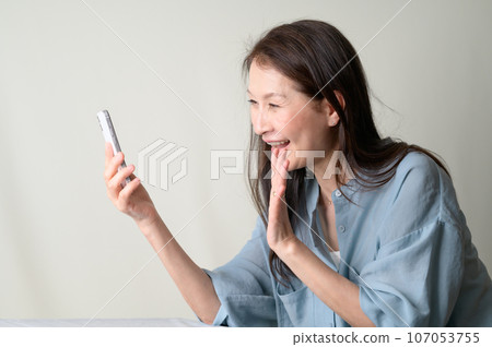 A smiling senior woman operating a smartphone 107053755