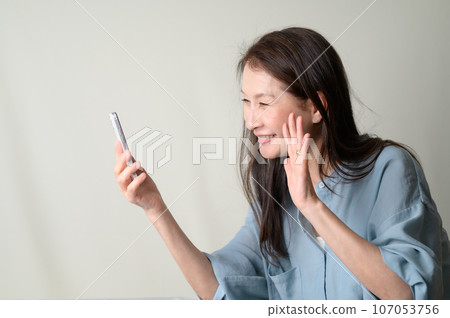 A smiling senior woman operating a smartphone A smiling senior woman operating a smartphone 107053756