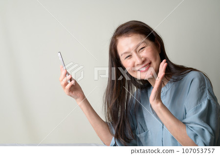 操作智能手機的微笑的資深婦女 107053757