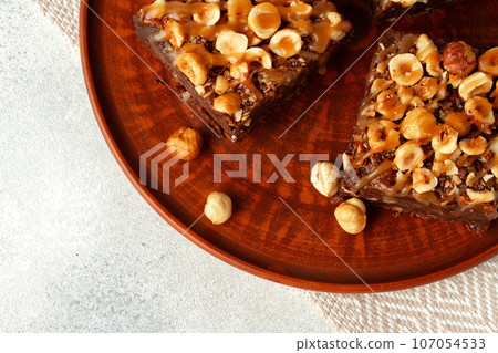 Brownie cake with nuts topping on plate close up Brownie cake with nuts topping on plate close up 107054533