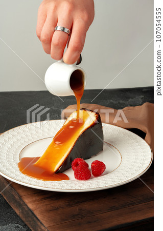 Piece of cheesecake with pouring caramel sauce on plate Piece of cheesecake with pouring caramel sauce on plate 107054555
