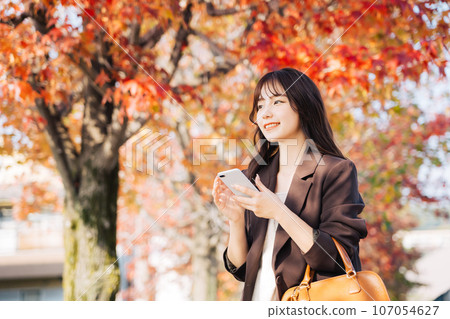 A woman going out during the autumn leaves season A woman going out during the autumn leaves season 107054627